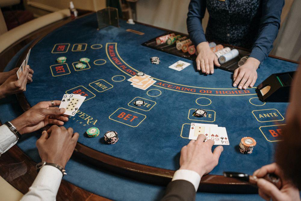 Pemain bermain kartu bersama dealer di meja kasino menggambarkan bonus rollingan